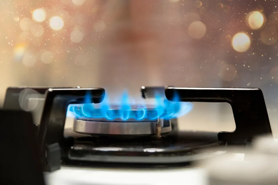 Close-up of lit burner on gas stove with blue flames
